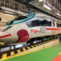 Ein ICE-Zug in der Werkstatt wird mit bunten Motiven beklebt.