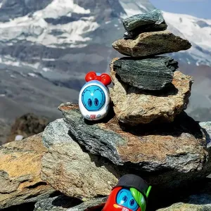 Spielfiguren Ida IC und Sally S-Bahn stehen auf einem Steinstapel im Hochgebirge