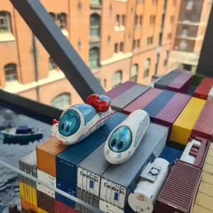 Spielfiguren Ida IC und der kleine ICE stehen auf Miniatur-Containern