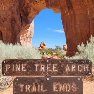 Spielfigur Sally S-Bahn steht auf einem Hinweisschild vor einem Wanderweg in Utah, USA.