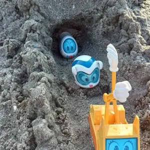 Verschiedene Spielfiguren kommen aus dem Tunnel einer Sandburg.