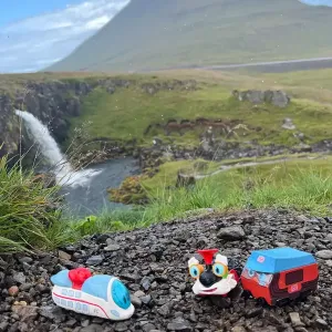 3 Spielfiguren stehen vor einem hohen Berg, vermutlich einem inaktiven Vulkan.