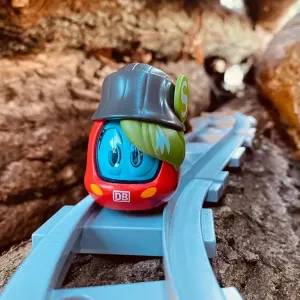 Figur Sally S-Bahn fährt über blaue Gleise zwischen Steinen.