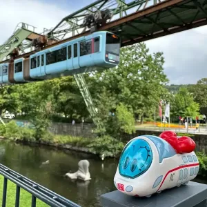 Figur Ida IC steht vor einem Kanal, über der eine Schwebebahn fährt. Ort: Wuppertal.