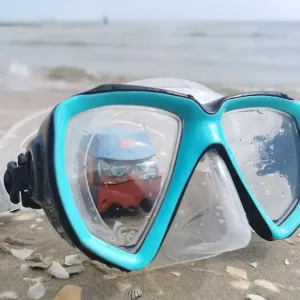 Figur Günni Güterzug schaut am Strand durch eine Taucherbrille.