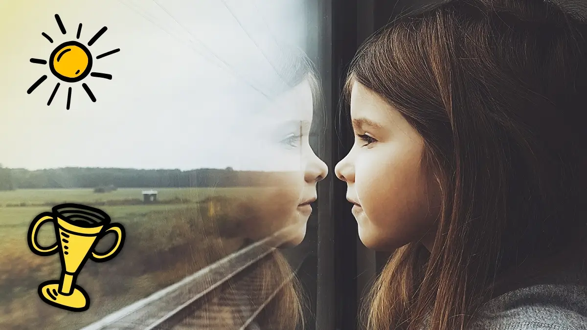 Ein Mädchen schaut durch ein Zugfenster in die Landschaft