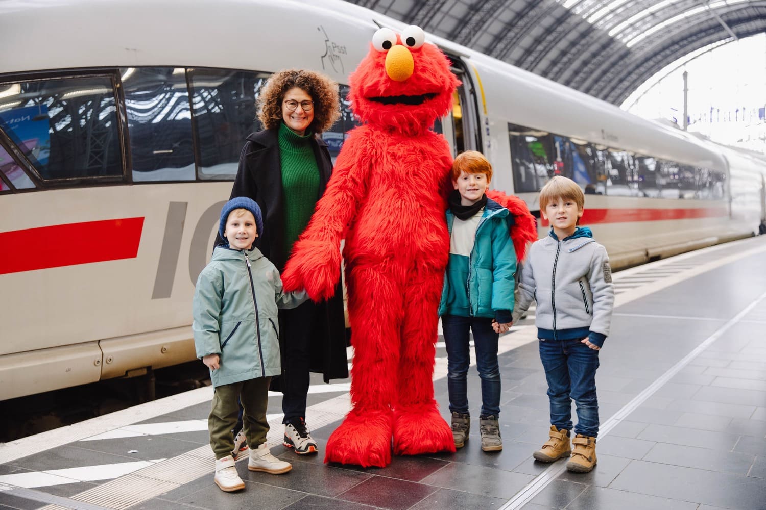 Kinder stehen mit einem Charakter aus der Sesamstraße auf einem Bahngleis vor einem ICE.