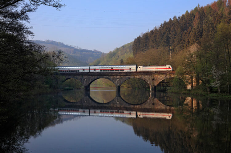 Ein ICE fährt über eine Bahnbrücke über einen Fluss