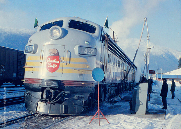 Lokomotive der Canadian Pacific mit Nummer 1432 steht im Schnee; Dampf steigt auf; zwei Personen am Rand.