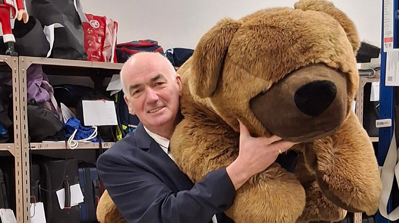 Udo Feld lächelt und hält einen riesigen braunen Teddybären im Arm.