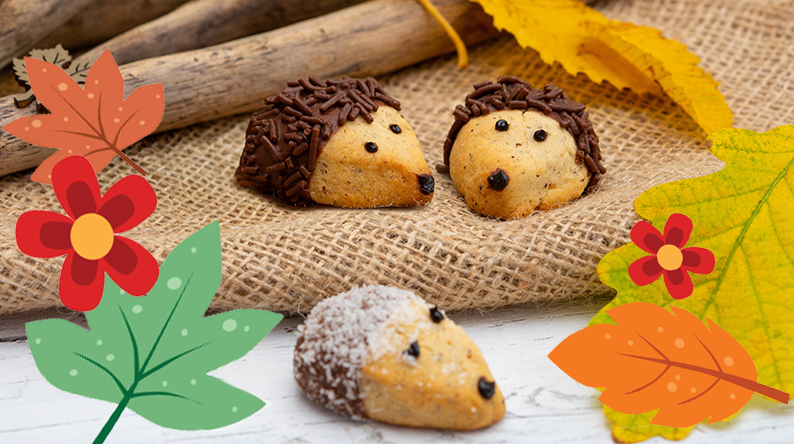 Drei Igel-Kekse auf einem Jutetuch zwischen Herbstblättern und Ästen.
