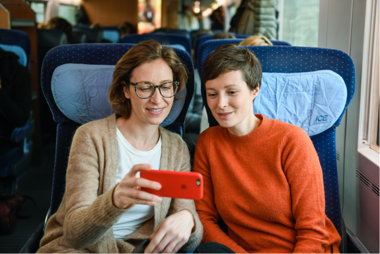 Zwei Frauen gucken im Zug etwas auf ihrem Handy