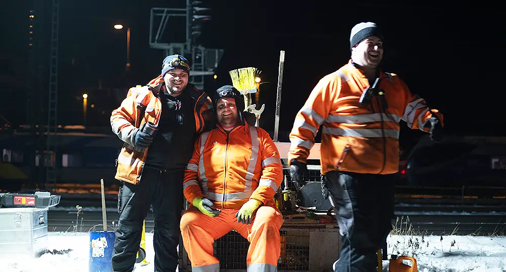 Drei Gleisarbeiter nachts bei der Arbeit