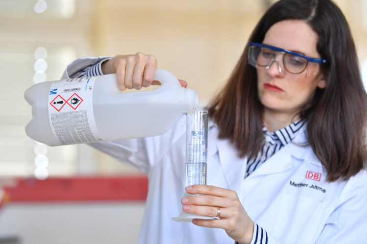 Laborarbeiterin füllt Flüssigkeit von einer Flasche in ein Reagensglas