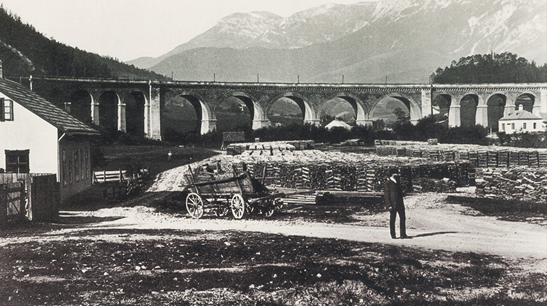 Altes Schwarz-Weiß-Foto einer Eisenbahnbrücke in den Bergen.