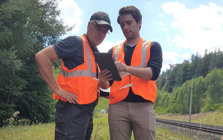 Zwei Mitarbeiter untersuchen Daten am Gleis