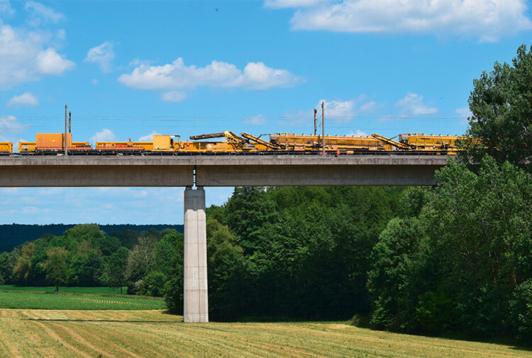 Die Gleisbettreinigungsmaschine fährt über eine Brücke