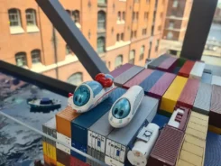 Spielfiguren Ida IC und der kleine ICE stehen auf Miniatur-Containern