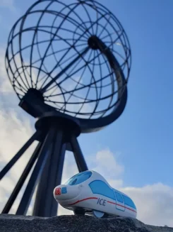 Figur der kleine ICE steht am Nordkap, im Hintergrund der Globus als Wahrzeichen.