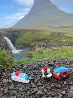 3 Spielfiguren stehen vor einem hohen Berg, vermutlich einem inaktiven Vulkan.