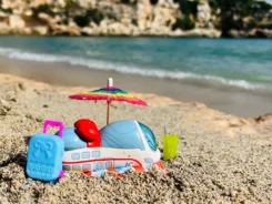 Figur Ida IC steht am Strand neben einem kleinen Sonnenschirm.