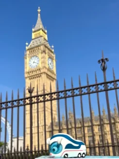 Figur Benni IC Bus steht in London vor dem Turm von Big Ben.