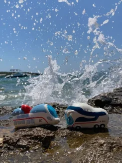 Figuren Ida IC und der kleine ICE stehen in einer spritzenden Welle am Meer