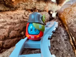 Figur Sally S-Bahn fährt über blaue Gleise zwischen Steinen.