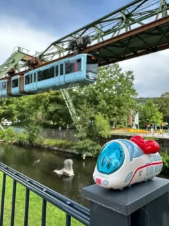 Figur Ida IC steht vor einem Kanal, über der eine Schwebebahn fährt. Ort: Wuppertal.