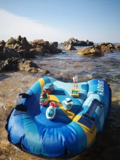 Diverse Spielfiguren stehen auf einer Luftmatratze am Strand.