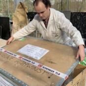 Ein Mann öffnet eine Holzkiste