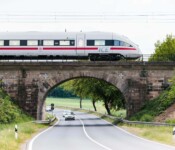 Ein ICE überquert eine Brücke über einer Landstraße