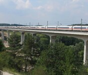ICE fährt über eine lange, weiße Eisenbahnbrücke