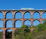 Ein Zug fährt über eine Brücke mit mehreren Bogenreihen