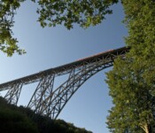 Eine Brücke fotografiert aus der Froschperspektive mit Bäumen am Rand