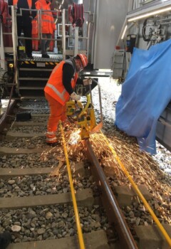 Letzter Schliff: Wo zwei Schienen aneinanderstoßen, wird der Übergang geglättet. So rollen die Züge geräuschloser drüber. © DB Netz/ Alexander_Ae_Paul Bahnarbeiter repariert Gleise, geschützt von der Überdachung der TVE