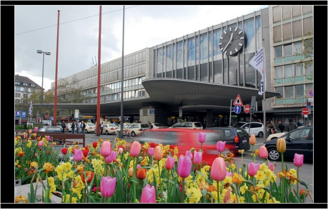 Schwarz-weiß und schlicht: die Bahnhofsuhr am Hauptbhanhof München. © Deutsche Bahn AG / Christian Bedeschinski Münchener Bahnhofshaupteingang mit Tulpen am Straßenrand